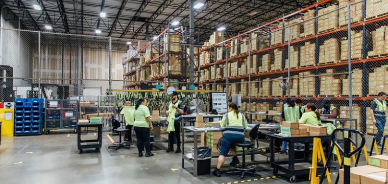 Warehouse workers sorting packages near tall shelves in a clean, organized facility